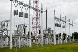 linha de transmissão de metal com os componentes da rede elétrica, o sistema de equipamentos de energia para a transmissão de eletricidade, corrente elétrica com o transformador na usina foto