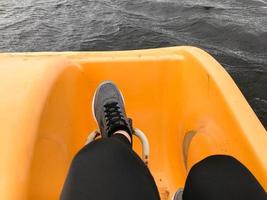 pernas em botas de tênis esporte cinza pedal em um catamarã amarelo foto