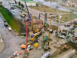 vista de uma altura de um grande canteiro de obras. construção de um viaduto no centro da cidade durante a chuva. máquinas de construção e guindastes no local foto