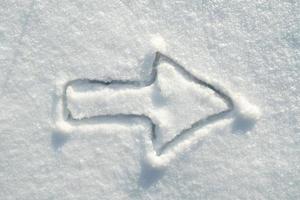 sinal de seta desenhando na neve, em um dia ensolarado. mover para a direita. copie o espaço. vista do topo. foto