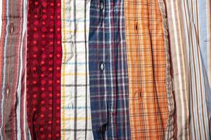 camisas amassadas de cores diferentes são empilhadas umas sobre as outras. fundo. foto