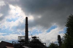 um grande tubo de ferro metálico não ecológico para a emissão de gás de fumaça na refinaria química petroquímica refinaria industrial contra o fundo do céu azul foto