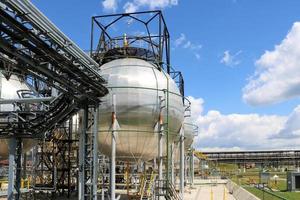 um grande tanque redondo de armazenamento de ferro de alta pressão metálico brilhante em forma de bola para amônia é forte com tubos e equipamentos na refinaria química petroquímica refinaria industrial foto