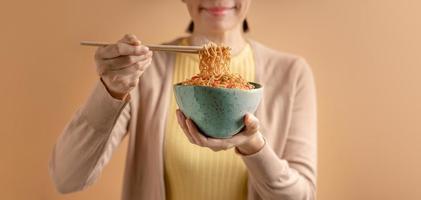 mulher usando pauzinhos para comer macarrão instantâneo cozido quente. conceitos de fast food asiáticos baratos. vista frontal foto