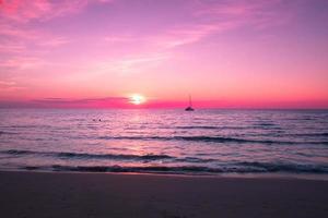 belo pôr do sol na praia, céu rosa no crepúsculo e reflexo no mar foto