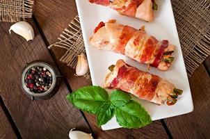 deliciosos rolinhos de frango recheados com feijão verde e cenoura envoltos em tiras de bacon