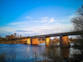 ponte antiga sobre o rio com pilares de pedra. fluxo rápido de água na primavera. vista do pôr do sol. foto