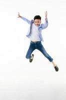 um menino asiático de 10 anos em uma jaqueta casual está pulando de forma inteligente e feliz olhando para a câmera contra um fundo branco isolado. foto