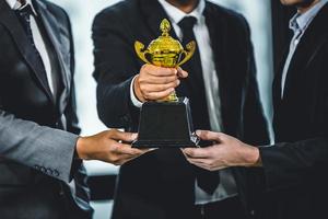 vitória da equipe de negócios ou conceito de sucesso, grupo de empresários segurando a taça vencedora de ouro foto