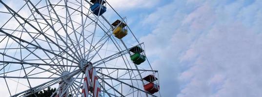 rodas gigantes coloridas no parque de diversões em um fundo de céu azul com nuvens. imagem tonificada. vista de baixo foto