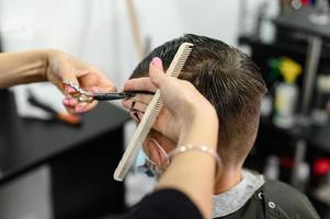 um adolescente em um salão de beleza corta o cabelo, um cabeleireiro corta o cabelo de um adolescente. foto