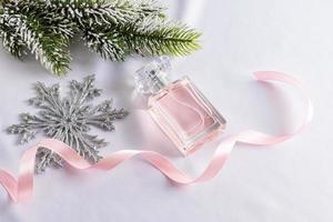 um frasco de perfume feminino floral no fundo das decorações de natal. o conceito de apresentação de um novo ano de uma fragrância ou presente.