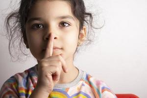 retrato de uma menina mostrando sinal para ficar em silêncio foto