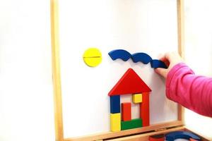 criança joga jogo educacional magnético de madeira. menina brinca com um brinquedo em um fundo branco. foto