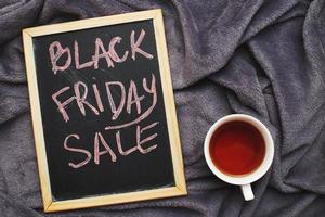 anúncio de venda de sexta-feira em um quadro-negro em tecido têxtil cinza fundo enrugado com xícara de chá foto