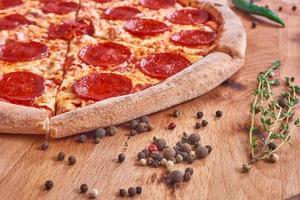 pizza de pepperoni e ervas em superfície de madeira