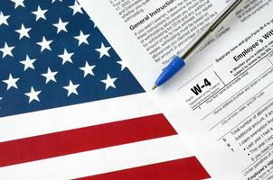 formulário w-4 certificado de subsídio de retenção do funcionário e caneta azul na bandeira dos estados unidos. formulário de imposto de renda interna foto