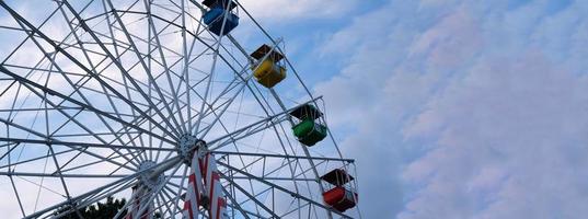 rodas gigantes coloridas no parque de diversões em um fundo de céu azul com nuvens. imagem tonificada. vista de baixo foto