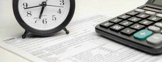 formulário de imposto com relógio, caneta e calculadora em fundo branco. conceito de negócios. foto