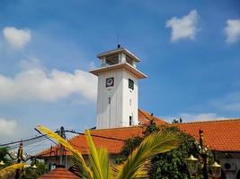 grande relógio de parede em um antigo prédio branco em madiun, java leste, indonésia, com um lindo céu azul brilhante. foto