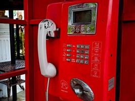 o antigo telefone com fio vermelho no passado, é como voltar ao passado, onde as pessoas costumavam usar telefones públicos. foto