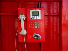 o antigo telefone com fio vermelho no passado, é como voltar ao passado, onde as pessoas costumavam usar telefones públicos. foto