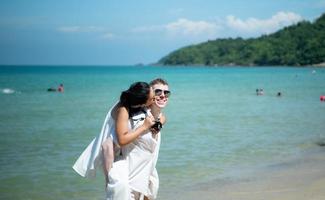 casal interracial com a alegria de viajar para o lindo mar azul como o paraíso foto