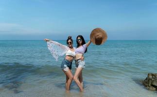 casais lgbt viajando pela ásia, nadam alegremente na praia com o lindo mar azul foto