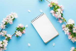 sakura de primavera florescendo em um fundo azul com espaço de bloco de notas para uma mensagem de saudação. o conceito de primavera e dia das mães. lindas flores delicadas de cerejeira rosa na primavera foto