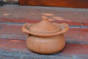 panela de barro está sobre a mesa em cerâmica situada na mesa de madeira. foto