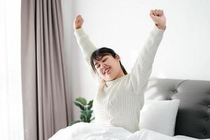 mulher feliz esticando os braços na cama pela manhã. foto