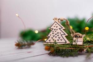 pingente de árvore de natal de madeira de presente artesanal em um fundo de guirlandas de natal bokeh e árvore de natal. decoração da árvore de natal na forma de um close-up da árvore de natal foto