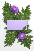 envelope vazio violeta e flores de cardo roxas em um fundo branco. maquete para convite ou cartão de felicitações. foto