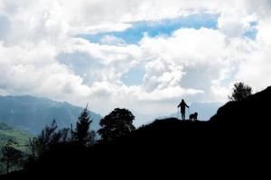 homem andando com seu cachorro nas montanhas foto