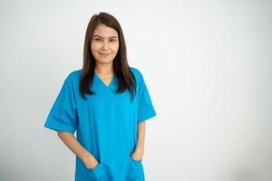 retrato de médica asiática confiante, feliz e sorridente, médica ou enfermeira vestindo uniforme de avental azul sobre fundo branco isolado foto