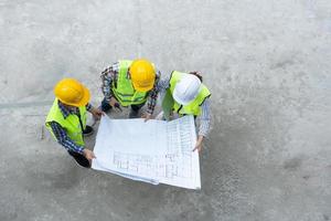 visão superior do engenheiro asiático ou jovem arquiteto feminino colocar um capacete para segurança e conversar com um empreiteiro em um projeto de fábrica de construção civil, conceito de trabalho em equipe, conceito de liderança. foto