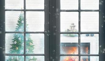 vista pela janela da árvore de natal e a lareira em um dia frio de inverno. o conceito de uma casa quente e reunião familiar durante o natal foto