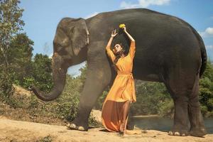 mulher em lindo vestido laranja e poderoso elefante foto
