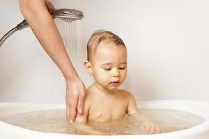 mãe lavando e banhando seu filho pequeno. foto