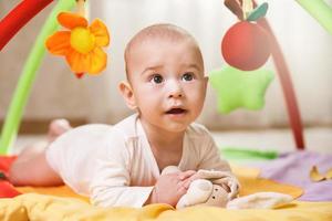 bebê fofo está brincando no tapete de atividades foto