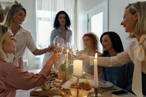 amigos de mulheres jovens tilintar de copos na mesa festiva. foto