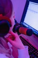 blogueira mulher usando microfone condensador durante podcast online em sala com luz neon foto