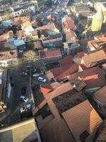 visão vertical do topo do alto de uma bela cidade turística com prédios e casas, telhados de árvores e plantas, natureza contra o céu azul e montanhas. arquitetura antiga europeia foto