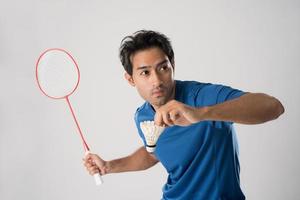 um jogador de badminton em roupas esportivas fica segurando uma raquete e peteca. foto