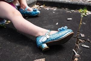 pernas de uma criança em lindos sapatos de salto alto azuis brilhantes, ao ar livre. foto