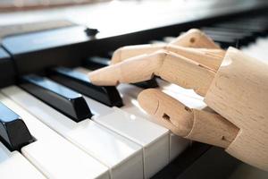 mão de madeira de um manequim toca piano, na luz natural da janela. foto