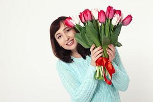 mulher bonita feliz com flores tulipas nas mãos sobre fundo branco foto