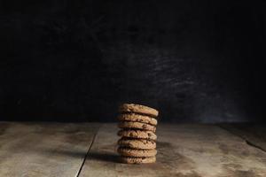 pilha de biscoitos de chocolate na mesa de madeira em fundo preto foto