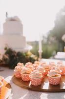 cupcakes gourmet com cobertura de creme de manteiga branco e confeitos em fundo de madeira foto