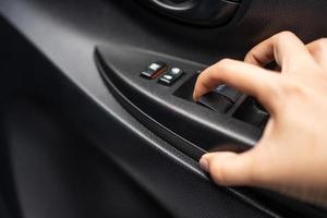 close-up da mão pressionando o botão da tampa da janela do carro. foto